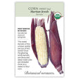 Seed packet for Martian Jewels sweet corn illustrating an ear with deep-violet husks peeled back to reveal pale creamy-white kernels, alongside a closed unpeeled ear, with text noting frost sensitivity, 80-90 day maturity, and USDA Organic certification.