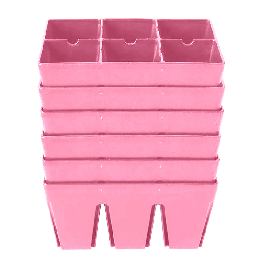 Six pink plastic seed-starting trays, each divided into six deep square cells, stacked in a tower against a plain white background.