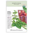 Seed packet for organic heirloom Lemon Balm featuring an illustration of small white flowers and crinkled green leaves beside a glass of iced tea, with text noting it's a perennial for full sun to part shade, sown after last spring frost.
