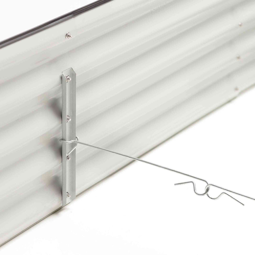 Close-up of the corrugated galvanized steel wall of a raised garden bed, showing a vertical bolted support bracket with a wire cross-brace bent into decorative curled ends for structural reinforcement.