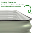 Close-up of a sage-green corrugated metal raised garden bed's rounded corner and black rubber safety edging, with on-image text headed "Safety Features" explaining that rounded corners and heavy-duty, UV-stable edging protect hands.