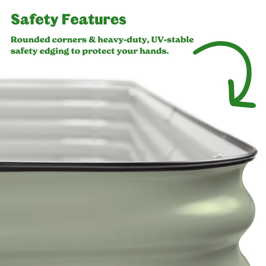 Close-up of a sage-green corrugated metal raised garden bed's rounded corner, showing its black UV-stable rubber safety edging, with text noting rounded corners and heavy-duty edging protect hands.