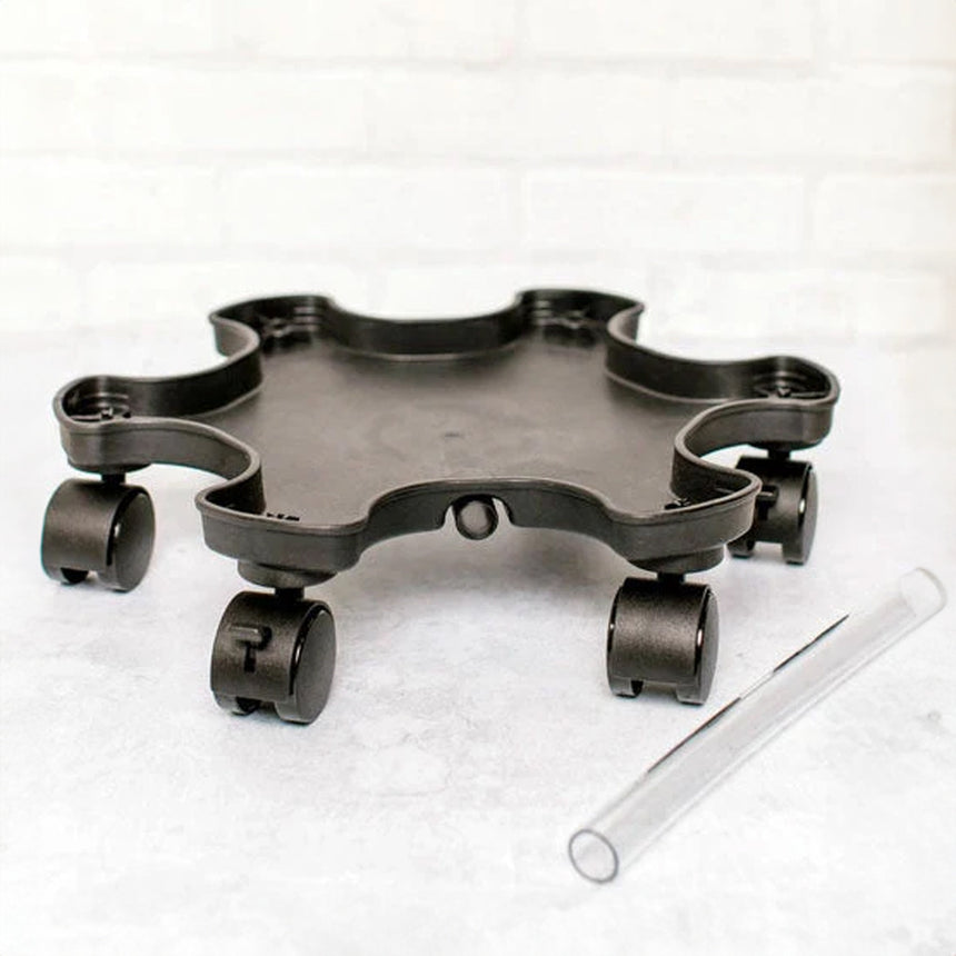 Black plastic star-shaped planter mover base with five lockable caster wheels around the rim, shown beside a clear plastic connecting tube, on a light marbled surface.