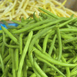 Close-up view of a freshly harvested heap of vibrant green, long, and slender Jade Bush Bean Seeds pods with pale yellow wax beans in the background.