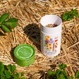 Opened canister of the Midwest Prairie Splendor Flower Mix Seed Shaker on a bed of straw with plants around them