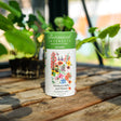 Botanical Interests Southern Hills and Plains Flower Mix Seed Shaker canister on a wooden surface with plants in the background